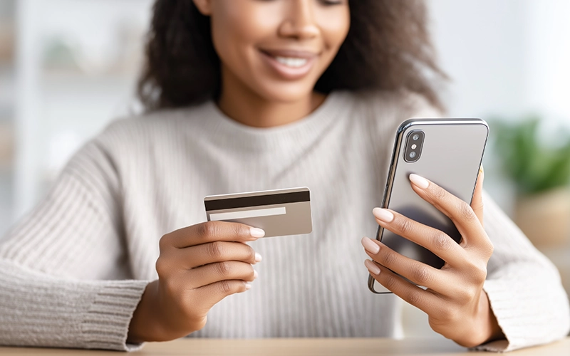 woman holding cell phone and a debit card